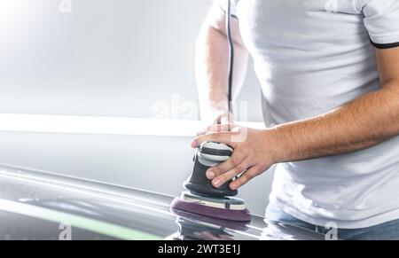 Detailing a cars concept, young man using orbital polisher for removing scratches from the car Stock Photo