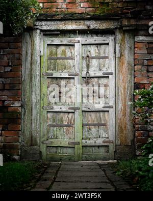 Old large wooden gates set in a brick wall of a cottage garden.  Rustic design with old middle eastern flavour to them Stock Photo