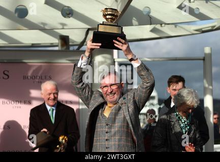 Greg Turley, husband of owner Audrey Turley lifts the trophy after winning the Boodles Cheltenham Gold Cup Steeple Chase which was ridden to victory by Paul Townend on day four of the 2024 Cheltenham Festival at Cheltenham Racecourse. Picture date: Friday March 15, 2024. Stock Photo