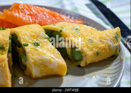 Chicken eggs omelette stuffed with green asparagus, served with smoked scottisch salmon fish, close up Stock Photo
