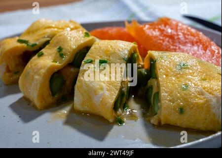 Chicken eggs omelette stuffed with green asparagus, served with smoked scottisch salmon fish, close up Stock Photo