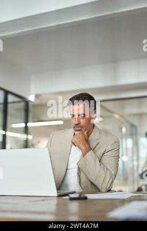Focused middle aged professional business man using laptop in corporate office. Stock Photo