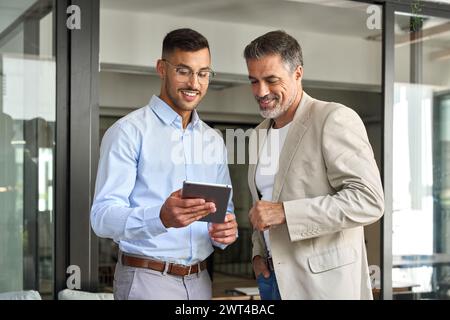 Team of two happy business men working standing in office using digital tablet. Stock Photo
