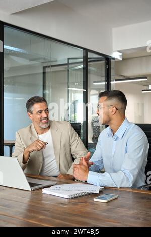 Two happy busy business men executives working using laptop in office. Vertical Stock Photo