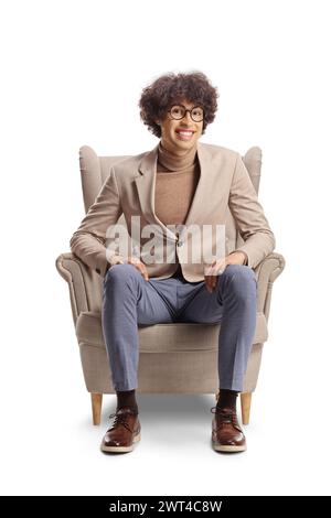 Young man with curly hair and glasses sitting in an armchair and smiling isolated on white background Stock Photo