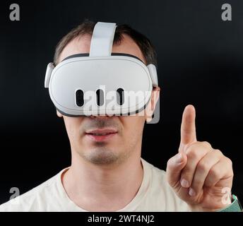New York, USA - March 15, 2024: Man uses Meta quest 3 portrait on black studio background Stock Photo