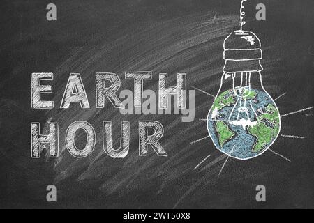 Light bulbs with lettering EARTH HOUR hand drawn in chalk on a school blackboard. Save the World. Save our planet. Stock Photo