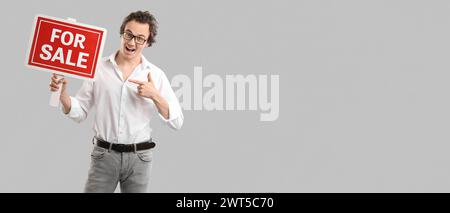 Real estate agent pointing at FOR SALE sign on grey background with space for text Stock Photo