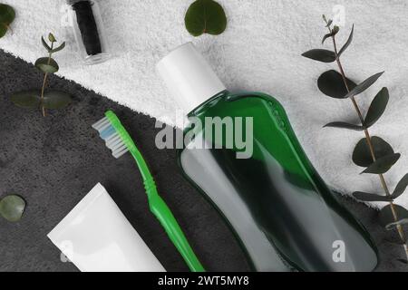 Fresh mouthwash in bottle, toothbrush, toothpaste and dental floss on dark textured table, flat lay Stock Photo