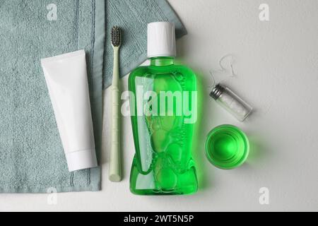 Fresh mouthwash in bottle, glass, toothbrush, toothpaste and dental floss on light background, flat lay Stock Photo