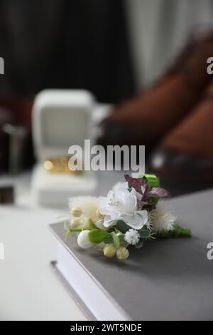 Wedding stuff. Composition with stylish boutonniere on white surface, closeup Stock Photo