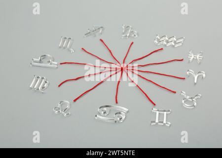 Zodiac compatibility. Signs and red threads on grey background Stock Photo