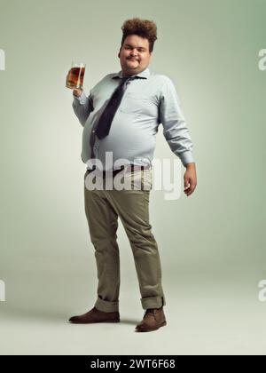 Plus size, portrait and man with beer in studio to enjoy drinking alcohol from pint glass for fun. Adult, guy and male person with smile, drunk and Stock Photo