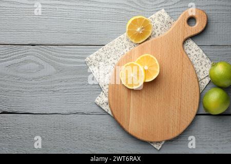Cutting board, lemon and limes on grey wooden table, flat lay. Space for text Stock Photo