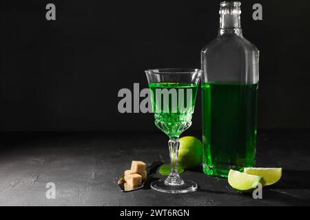 Absinthe, spoon, brown sugar and lime on black table, space for text. Alcoholic drink Stock Photo