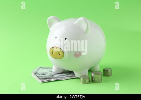 Financial savings. Piggy bank, dollar banknotes and stacked coins on green background Stock Photo
