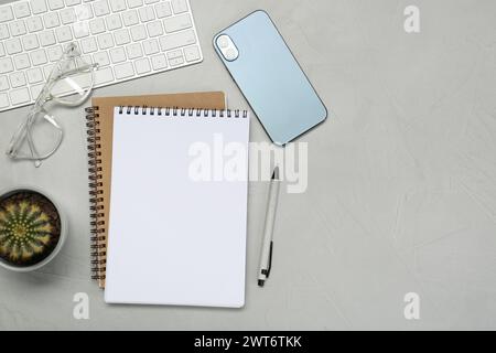 Flat lay composition with notebooks, smartphone, glasses and pen on light grey table Stock Photo
