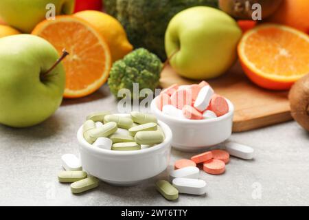 Dietary supplements. Different pills in bowls and food products on grey table Stock Photo