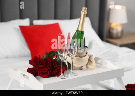 Honeymoon. Sparkling wine, glasses and bouquet of roses on table in room Stock Photo