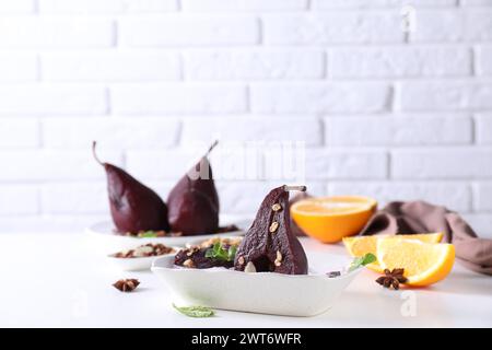 Tasty red wine poached pears with muesli in bowl on white table Stock Photo