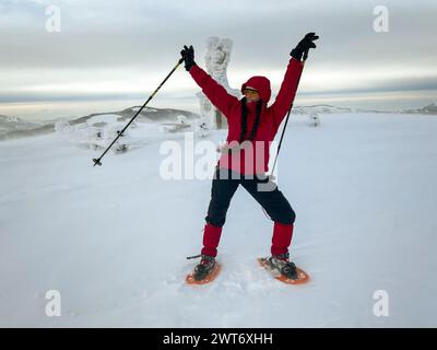 happy smiling girl in red jacket playing on top of a snowy mountain in winter Stock Photo