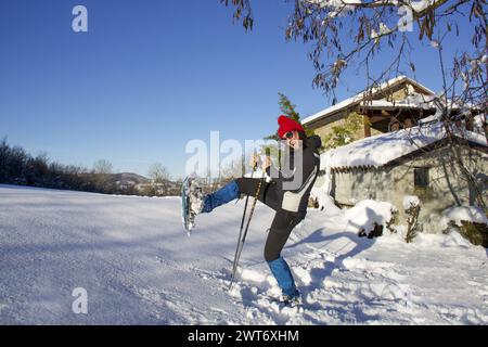 happy smiling girl in black jacket playing in the snow with snowshoes Stock Photo
