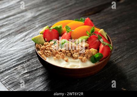 A Bowl of Homemade Granola with Yogurt and Fresh Avocado, Strawberry, and Apricot. On Wooden Background Stock Photo