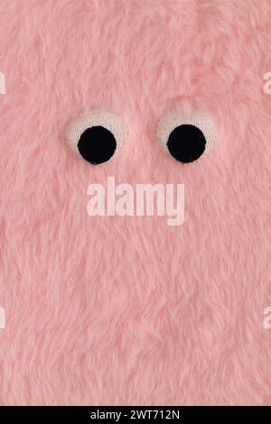 Cute fluffy monster made with pastel pink faux fur. Minimal concept. Creative funny face composition. An original peachy pink fur background image Stock Photo