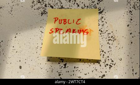 Text with the words "public speaking" on a note pasted on the wall Stock Photo