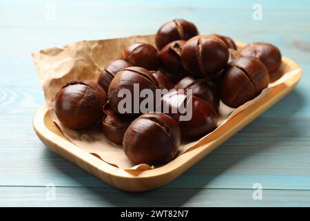 Fresh edible sweet chestnuts in serving plate on light blue wooden table Stock Photo