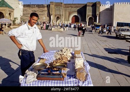 Meknes, Morocco.  Place Hedime Candy Vendor.  Bab Mansour in Background, built 1672-1732, entrance to the imperial quarter. Stock Photo