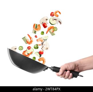 Man tossing ingredients in wok on white background, closeup Stock Photo