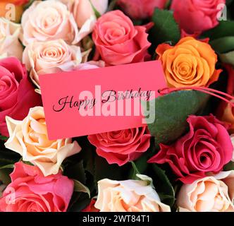 Bouquet of beautiful roses with Happy Birthday card, closeup Stock Photo
