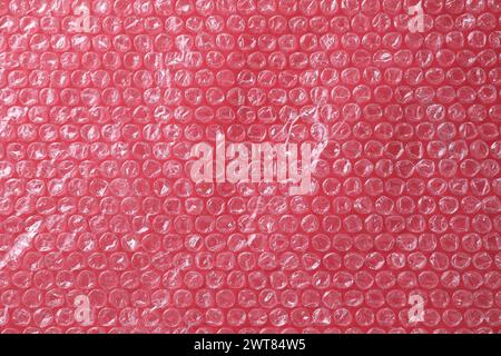 Transparent bubble wrap on red background, top view Stock Photo