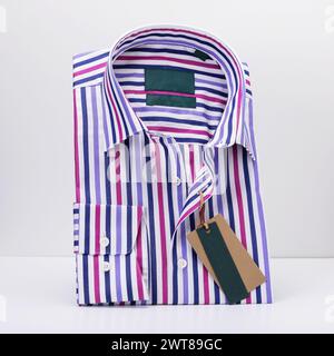 Classic folded men's shirt in colored stripes with long sleeves on a light background standing on a stand Stock Photo