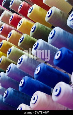 Assorted spools of multi-coloured cotton threads, abstract textile industry background Stock Photo