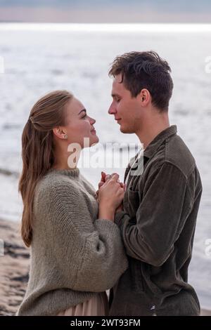 Against the shimmering sea, a couple shares a quiet moment of intimacy, their close embrace capturing the essence of seaside romance, a aesthetic date Stock Photo