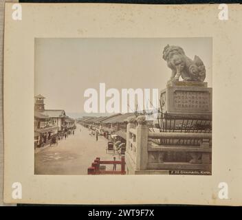 Gionmachi, Kioto. Attributed to Adolfo Farsari, photographer (American, 1841 - 1898) about 1882–1890s Looking westward along the busy Shijo Street (Shijo-dori) from the western gate of Yasaka Shrine, also known as Gion Shrine. Visible in the foreground is one of the two guardian dog statues that flank the steps of the gate. A watchtower can be seen on the center left area of the image. (Recto, print) lower right, printed in the negative: 'F 29 Gionmachi, Kioto.'; Stock Photo