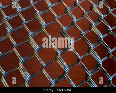 Texture of metal grid with cells on the red background, selective focus. Metallic mesh Stock Photo