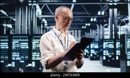 Skilled IT professional expertly managing data while navigating in industrial server room. Expert ensuring flawless cybersecurity protection, optimizing systems and perform necessary updates Stock Photo
