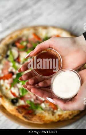 pizza sauces in hands on pizza background Stock Photo