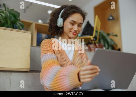 A happy woman with headphones smiles while using a tablet computer Stock Photo