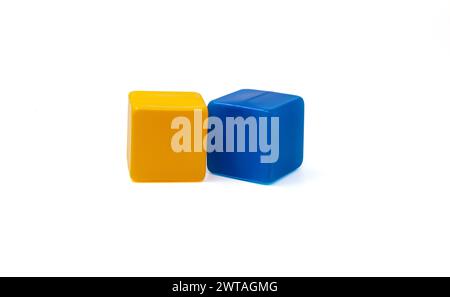 Multicoloured plastic cubes for children's games. Yellow and blue cubes lying side by side. White background. One near the other. Horizontal. Stock Photo