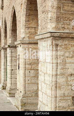 Old brick wall with arches. Weathered surface of the wall. Grunge style brick wall background. Weathered facade of a building. Vertical. Stock Photo