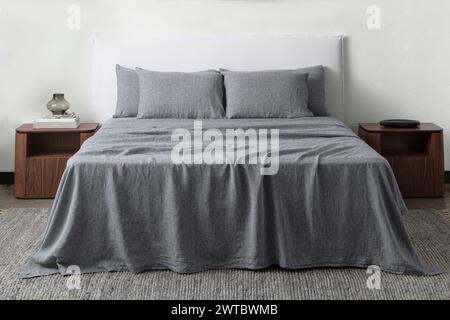 comfortable bed with pillows in contemporary room. interior design wall mock up. white bedroom with rug and white wall above bed.front view. Stock Photo