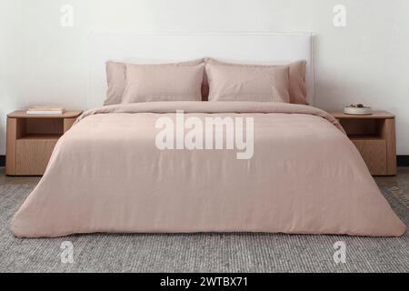 comfortable bed with pillows in contemporary room. interior design wall mock up. white bedroom with rug and white wall above bed.front view. Stock Photo