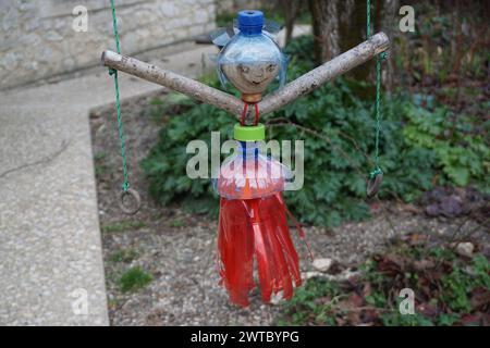 closeup on a recycled plastic bottle as a doll hanging like a swing in the garden in france Stock Photo