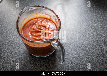 Stirring enchilada red sauce in glass measure jar. Stock Photo