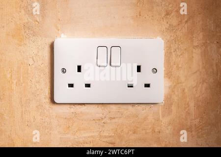 light switch on rough plastered wall texture closeup during home renovation. Stock Photo