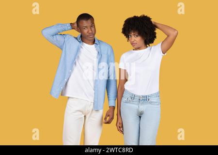 Two puzzled young adults in casual attire with a quizzical expression standing back to back Stock Photo